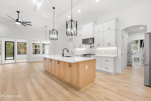 kitchen featuring arched walkways, white cabinetry, light countertops, and a large island