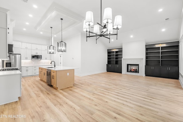 kitchen featuring white cabinets, light countertops, appliances with stainless steel finishes, open floor plan, and a kitchen island with sink