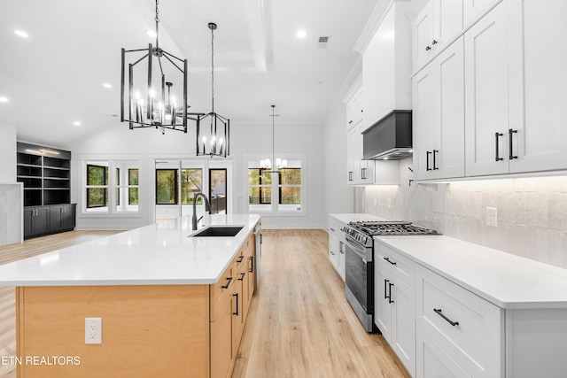 kitchen with a spacious island, an inviting chandelier, stainless steel gas stove, light countertops, and white cabinetry