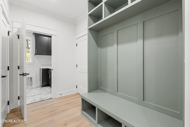 mudroom featuring crown molding, baseboards, and light wood-style floors