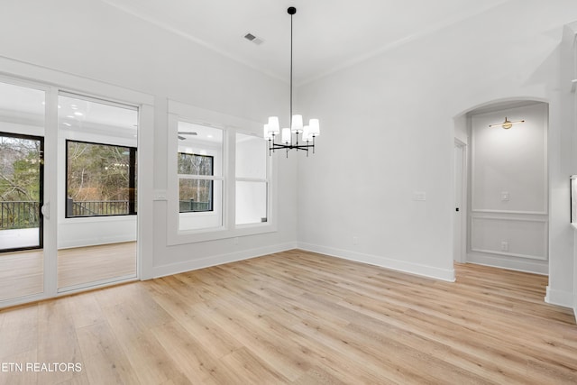 unfurnished dining area featuring light wood-style floors, baseboards, arched walkways, visible vents, and an inviting chandelier