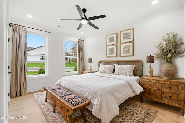 bedroom with multiple windows, light wood finished floors, ornamental molding, and visible vents