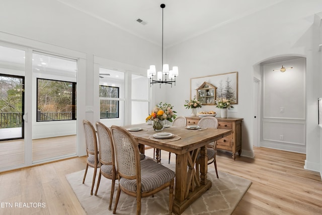 dining space featuring light wood-style flooring, arched walkways, an inviting chandelier, and visible vents