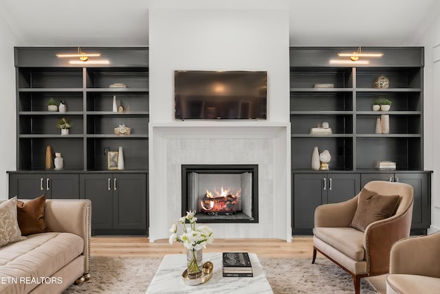 living room featuring a fireplace, built in shelves, and light wood-type flooring