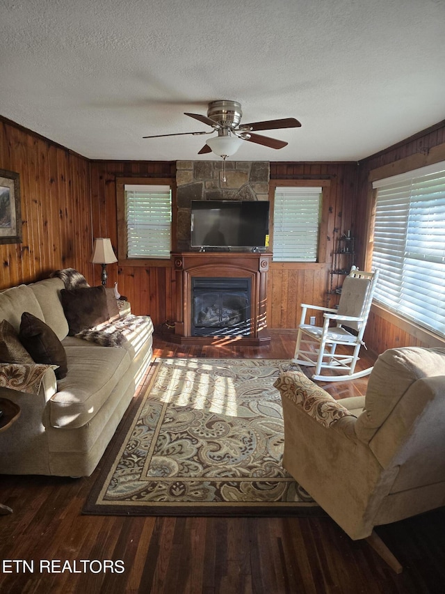 living room with hardwood / wood-style flooring, a large fireplace, a textured ceiling, and wood walls