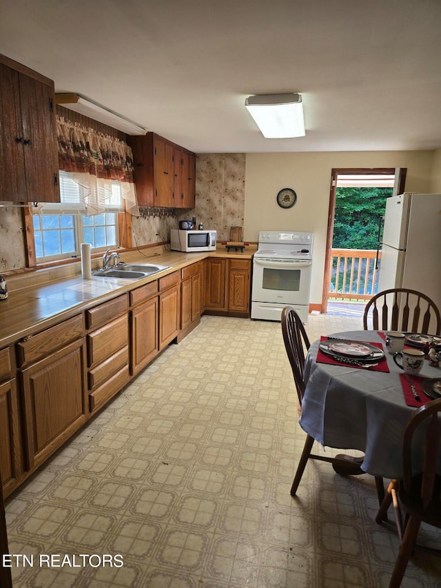 kitchen featuring backsplash, white appliances, and sink