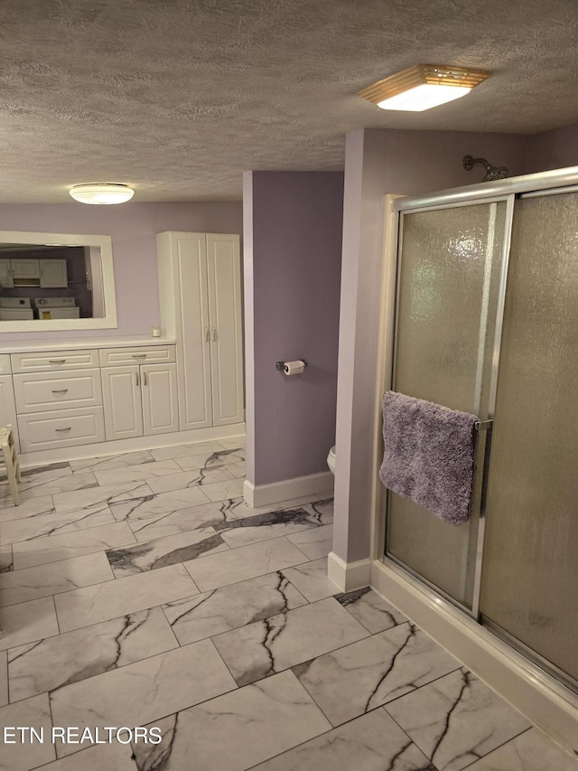 bathroom featuring toilet, a shower with door, and a textured ceiling