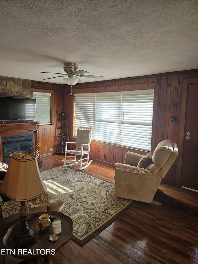 living room with wooden walls, dark hardwood / wood-style floors, and a textured ceiling