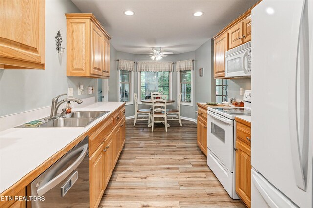 kitchen featuring light wood finished floors, recessed lighting, light countertops, a sink, and white appliances