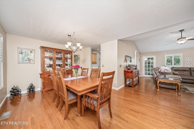 dining area with light wood-type flooring, visible vents, lofted ceiling, and baseboards