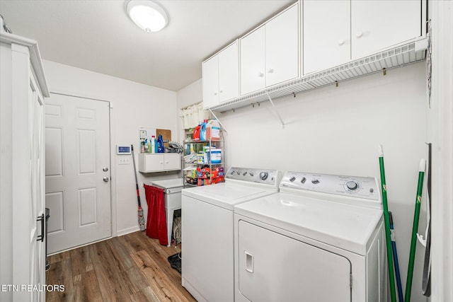 washroom with cabinet space, dark wood finished floors, and washing machine and clothes dryer