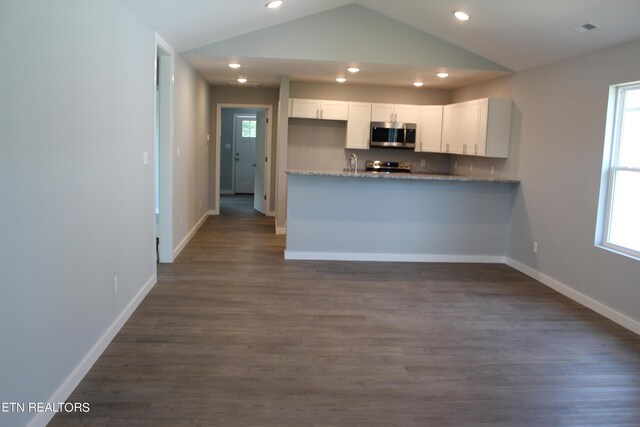 kitchen with vaulted ceiling, white cabinets, dark wood-type flooring, and kitchen peninsula