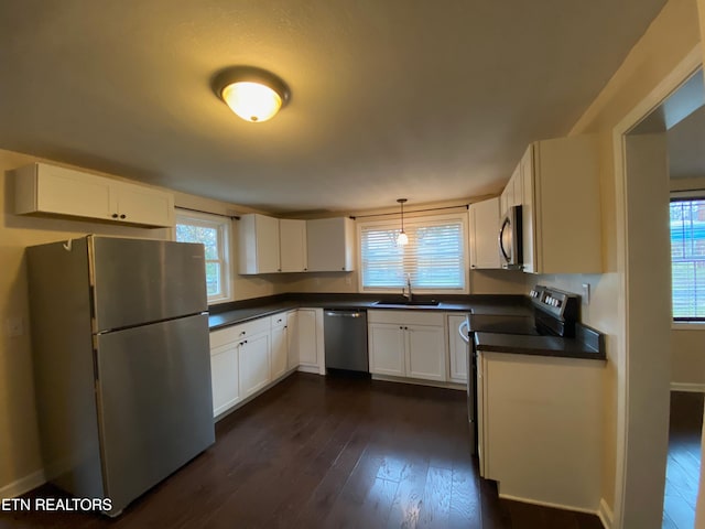 kitchen with dark hardwood / wood-style floors, pendant lighting, white cabinets, sink, and stainless steel appliances