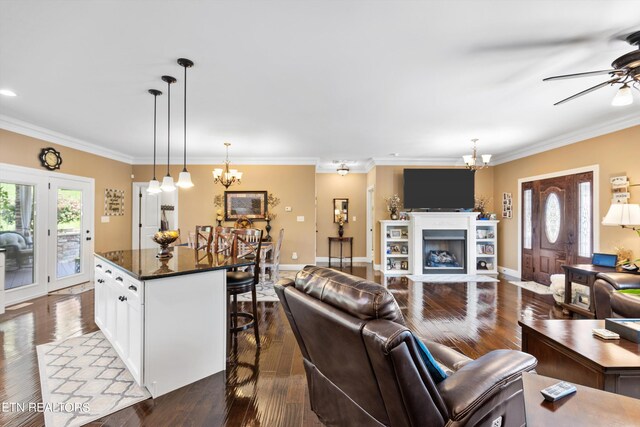 living room with dark hardwood / wood-style floors, ceiling fan with notable chandelier, and crown molding