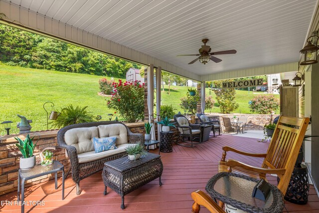 wooden deck featuring ceiling fan, outdoor lounge area, and a yard