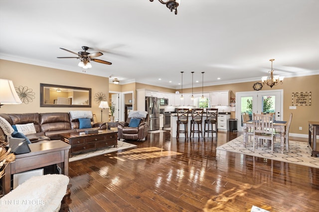 living room with ceiling fan with notable chandelier, dark wood-type flooring, and crown molding