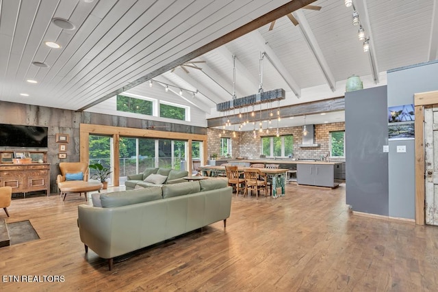 living room featuring beam ceiling, hardwood / wood-style flooring, high vaulted ceiling, an inviting chandelier, and track lighting