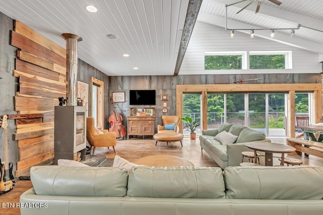 living room with wood walls, vaulted ceiling with beams, and a healthy amount of sunlight