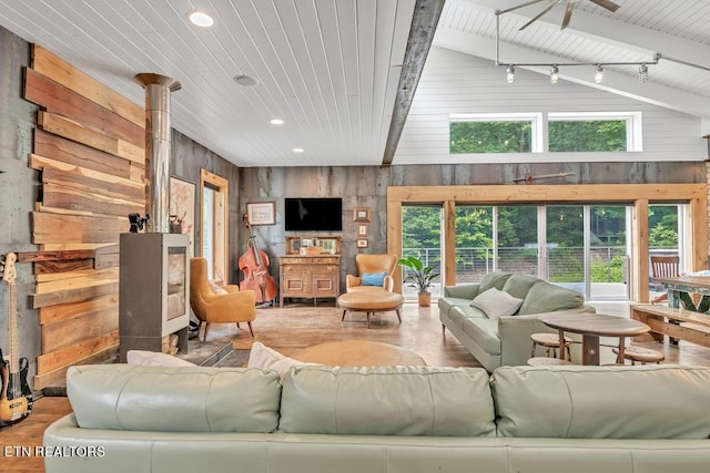 living room with wooden walls, beamed ceiling, rail lighting, wood ceiling, and light hardwood / wood-style flooring