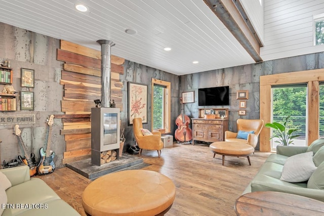 living room with beamed ceiling, a wood stove, and light wood-type flooring