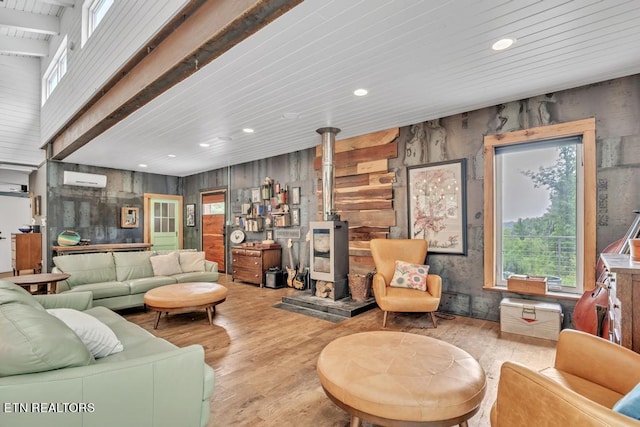 living room featuring beamed ceiling, light wood-type flooring, wooden walls, a wood stove, and a wall mounted AC