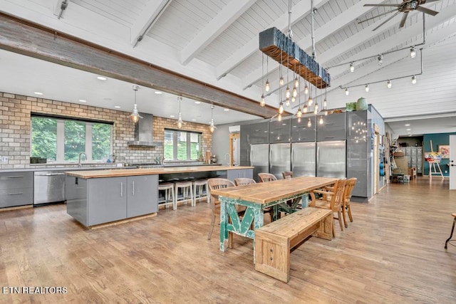 dining space featuring rail lighting, light hardwood / wood-style flooring, beam ceiling, and ceiling fan