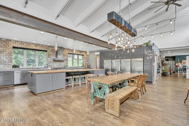 dining space with lofted ceiling with beams, ceiling fan, and light wood-type flooring