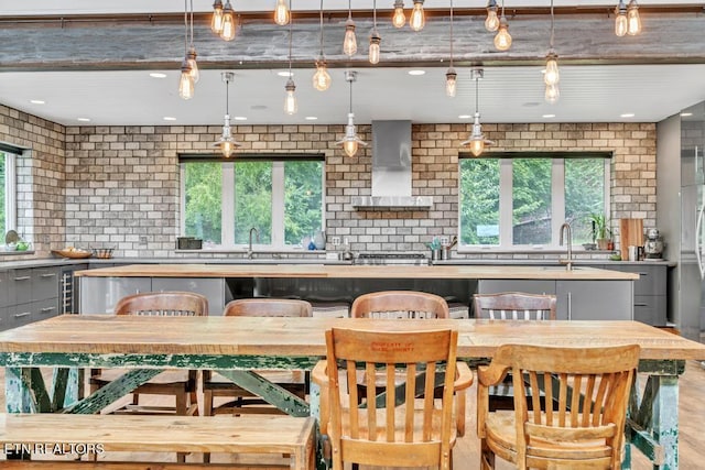 kitchen featuring gray cabinets, hanging light fixtures, backsplash, a kitchen island, and wall chimney exhaust hood