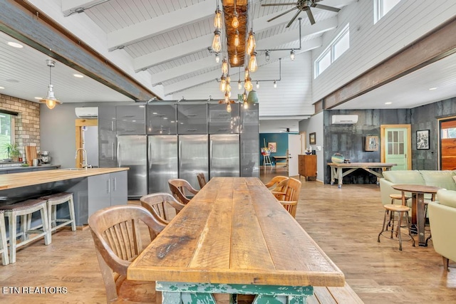 dining room featuring ceiling fan, light wood-type flooring, a wall mounted AC, and a high ceiling