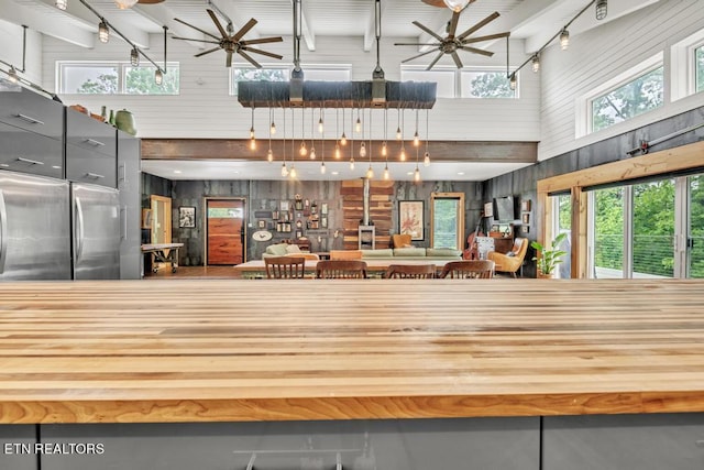 kitchen featuring ceiling fan, a towering ceiling, stainless steel refrigerator, wood counters, and high end refrigerator