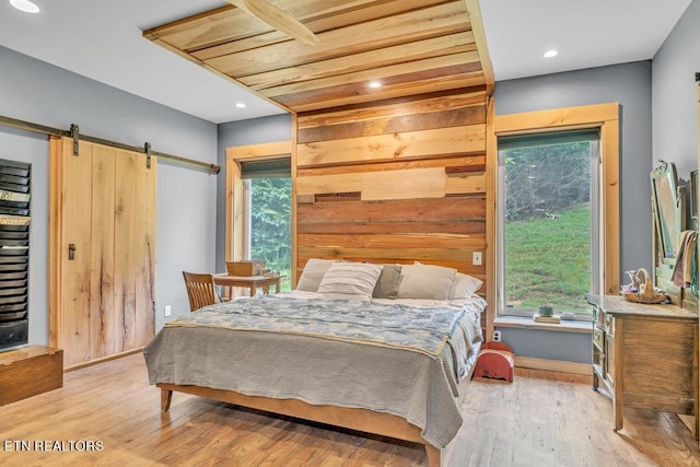 bedroom with multiple windows, a barn door, and light hardwood / wood-style flooring