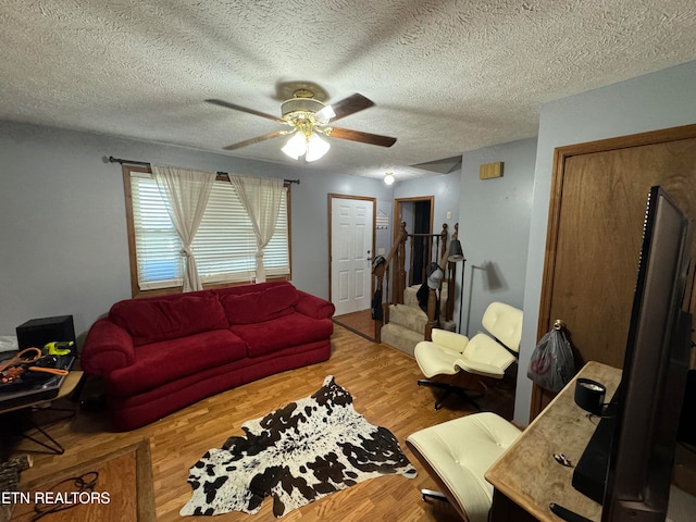 living room featuring ceiling fan, a textured ceiling, and wood-type flooring