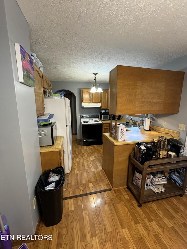 kitchen featuring pendant lighting, sink, electric range oven, light hardwood / wood-style floors, and kitchen peninsula