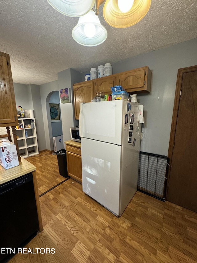 kitchen with white refrigerator, dishwasher, light hardwood / wood-style floors, and a textured ceiling