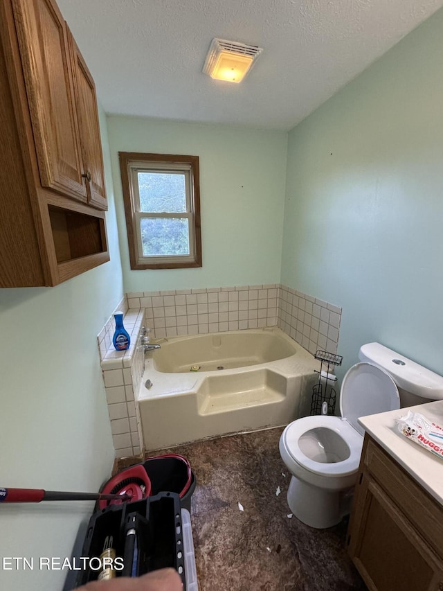 bathroom featuring vanity, a tub to relax in, a textured ceiling, and toilet