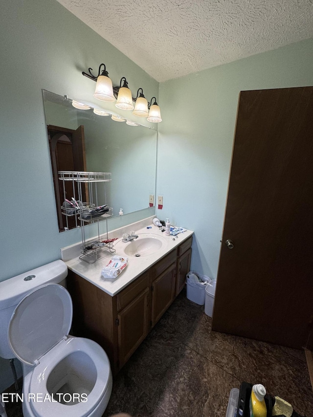 bathroom featuring vanity, toilet, and a textured ceiling