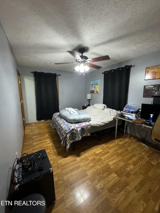 bedroom featuring ceiling fan, hardwood / wood-style floors, and a textured ceiling