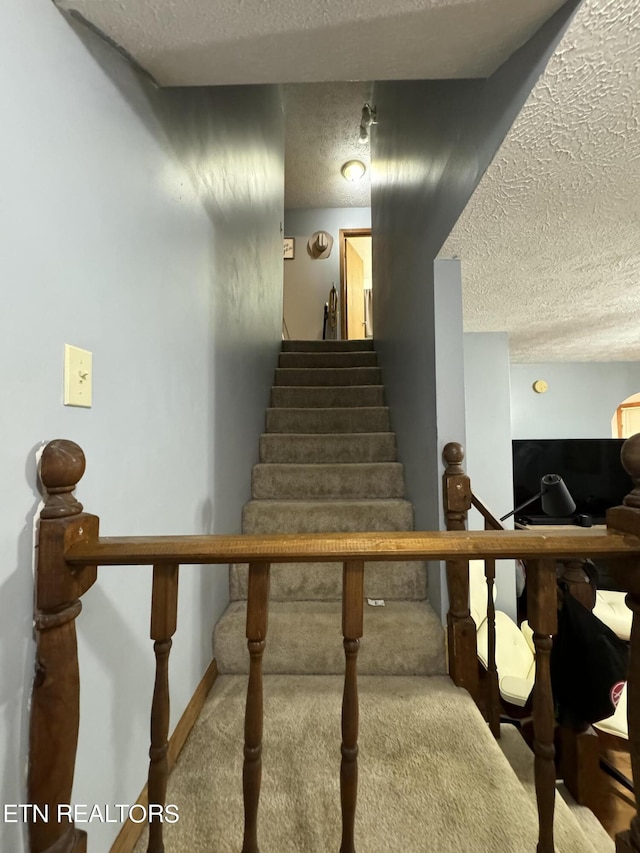 staircase with carpet and a textured ceiling