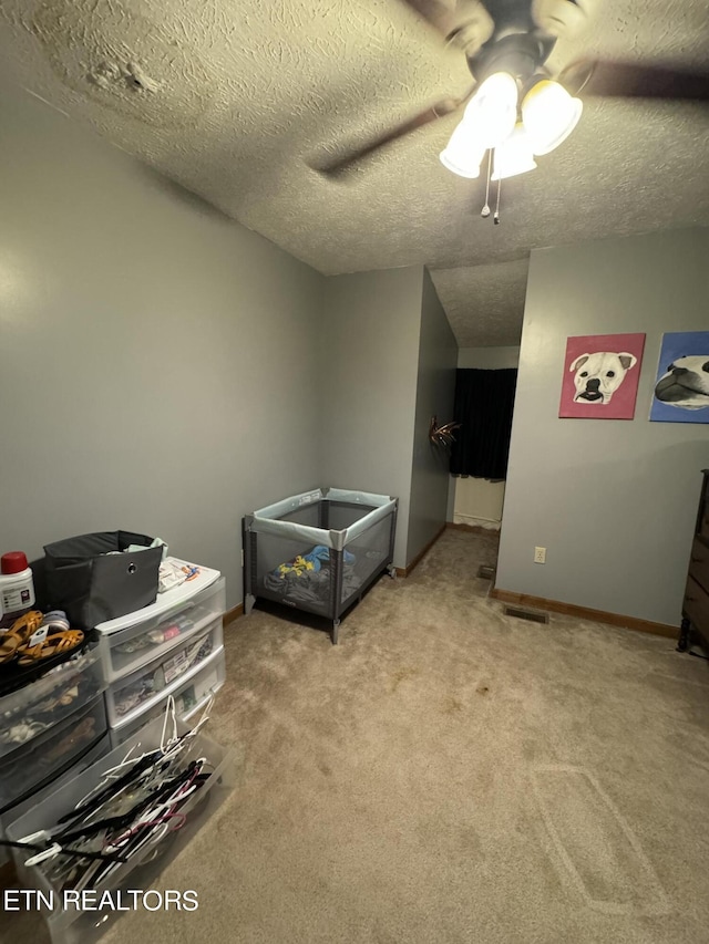 bedroom with ceiling fan, light colored carpet, and a textured ceiling