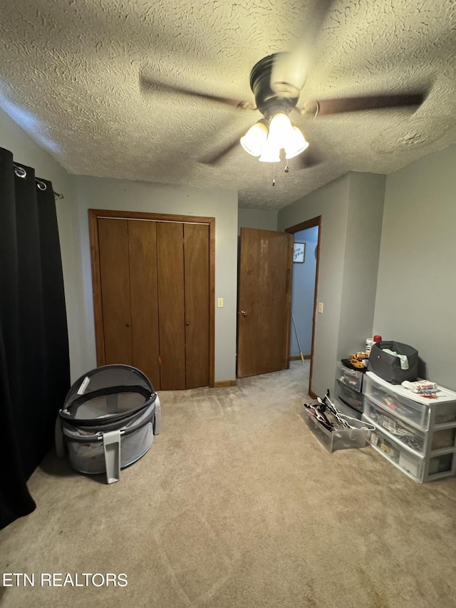 misc room featuring ceiling fan, light colored carpet, and a textured ceiling