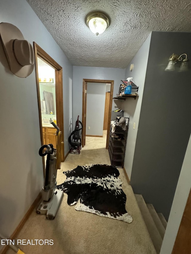 hall featuring light colored carpet, sink, and a textured ceiling