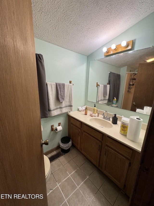 bathroom with tile patterned flooring, vanity, a textured ceiling, curtained shower, and toilet