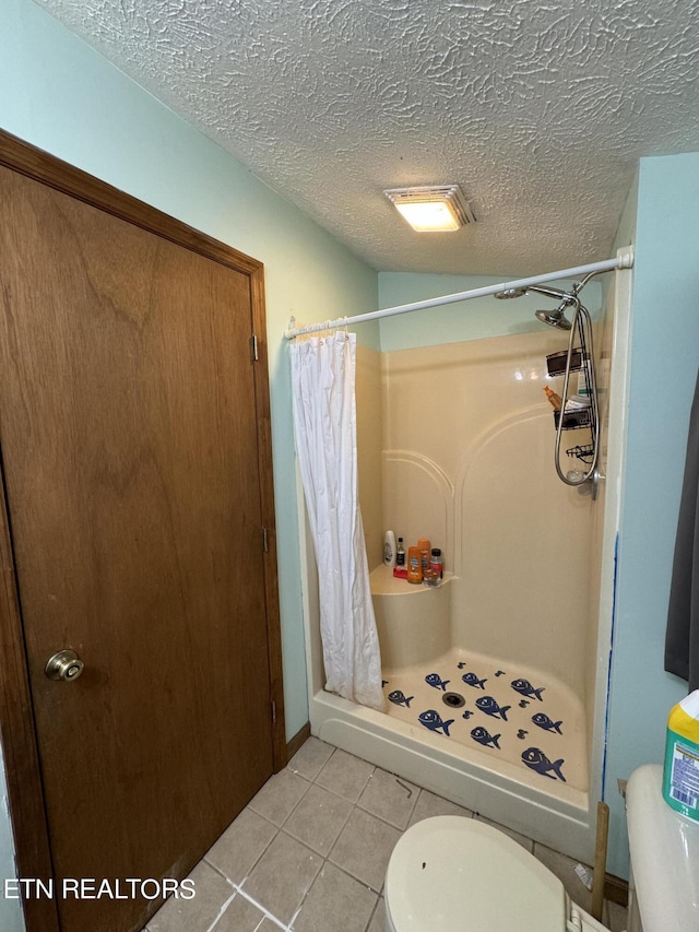 bathroom featuring toilet, tile patterned floors, a textured ceiling, and a shower with curtain