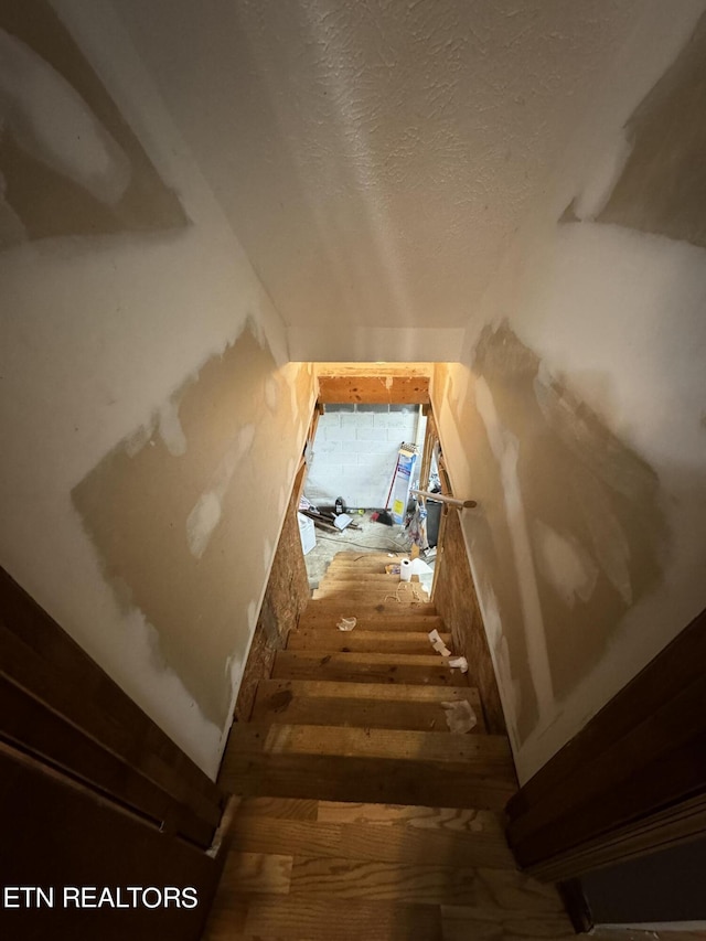 stairs featuring a textured ceiling