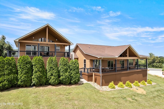 rear view of house featuring a balcony and a lawn