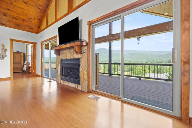 unfurnished living room featuring hardwood / wood-style floors, high vaulted ceiling, a stone fireplace, and wood ceiling