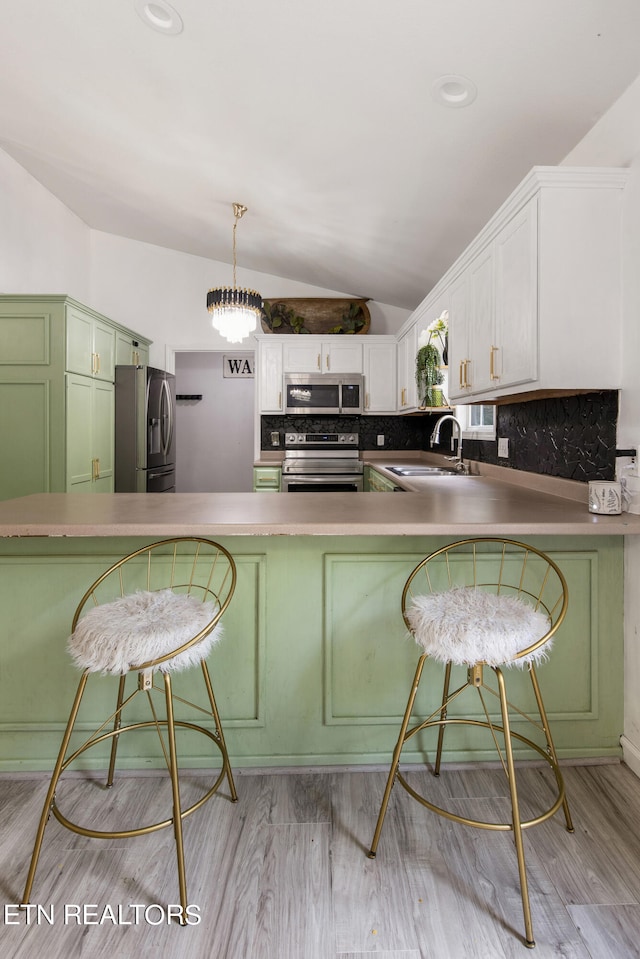 kitchen with vaulted ceiling, stainless steel appliances, light hardwood / wood-style flooring, and sink