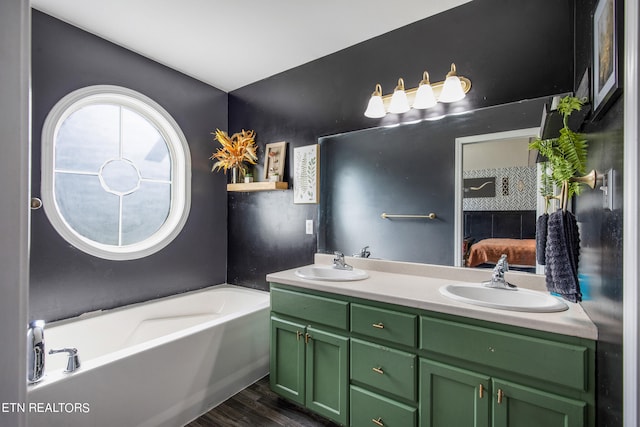 bathroom featuring wood-type flooring, a tub to relax in, and vanity