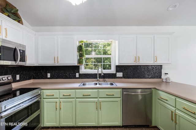 kitchen featuring appliances with stainless steel finishes, backsplash, sink, lofted ceiling, and white cabinets