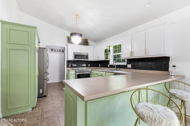 kitchen featuring appliances with stainless steel finishes, kitchen peninsula, backsplash, and lofted ceiling